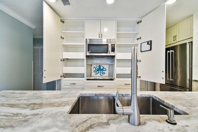 kitchen featuring stainless steel appliances, sink, crown molding, white cabinets, and light stone counters