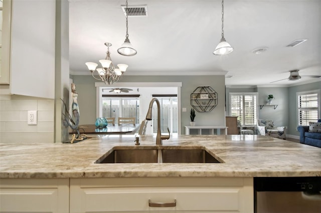 kitchen with dishwasher, decorative backsplash, sink, light stone countertops, and decorative light fixtures