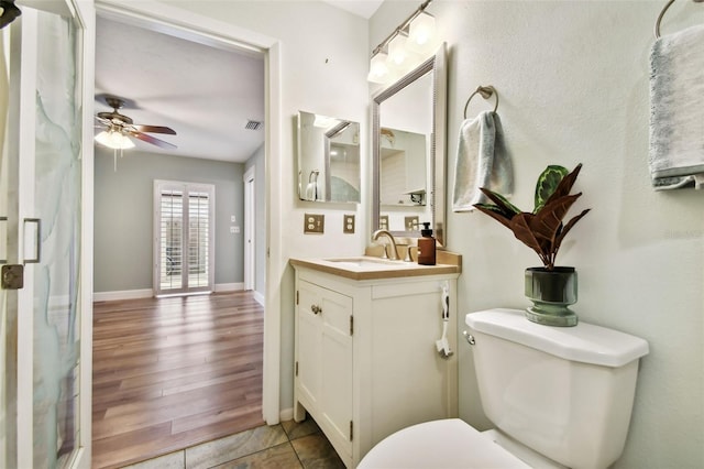 bathroom with toilet, wood-type flooring, ceiling fan, vanity, and walk in shower