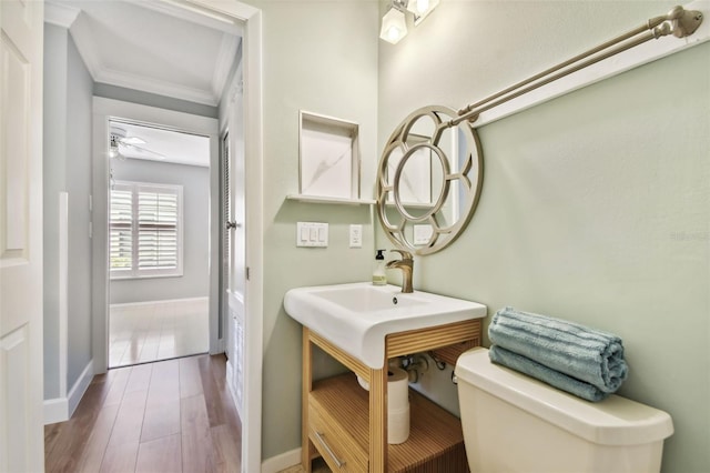 bathroom featuring toilet, crown molding, and hardwood / wood-style flooring