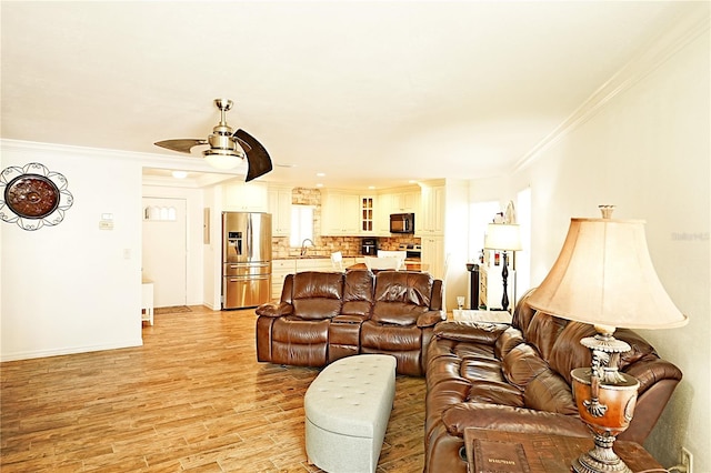 living room with ornate columns, sink, crown molding, light wood-type flooring, and ceiling fan