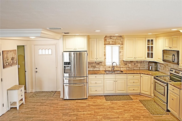 kitchen with stainless steel appliances, sink, crown molding, stone counters, and light hardwood / wood-style floors