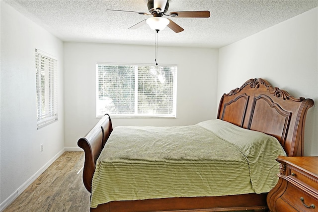 bedroom featuring a textured ceiling, multiple windows, light wood-type flooring, and ceiling fan