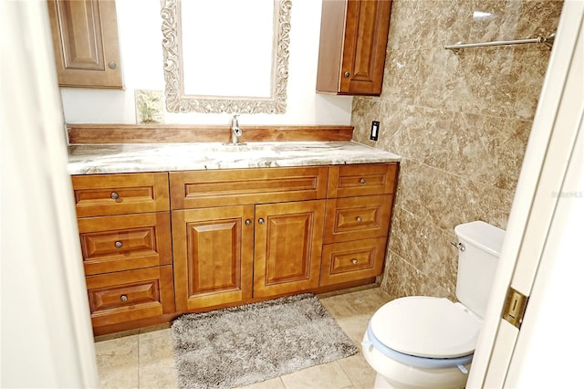 bathroom with toilet, vanity, tile patterned floors, and tile walls