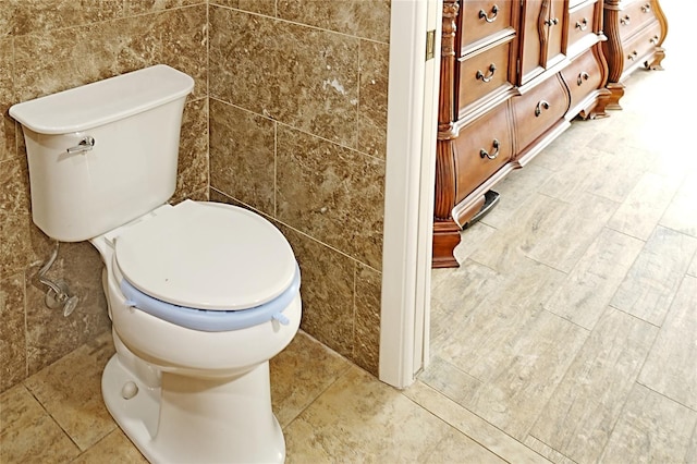 bathroom featuring toilet and tile walls