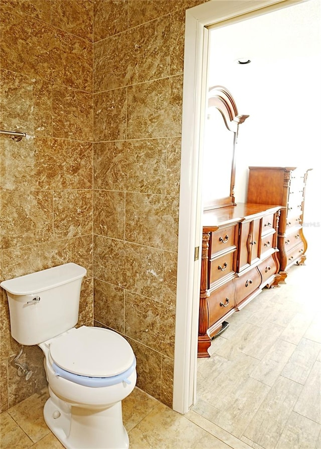 bathroom featuring toilet and tile walls