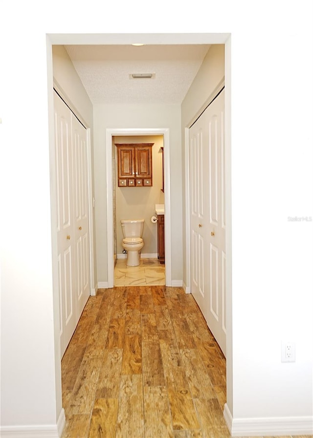 hall featuring a textured ceiling and light wood-type flooring