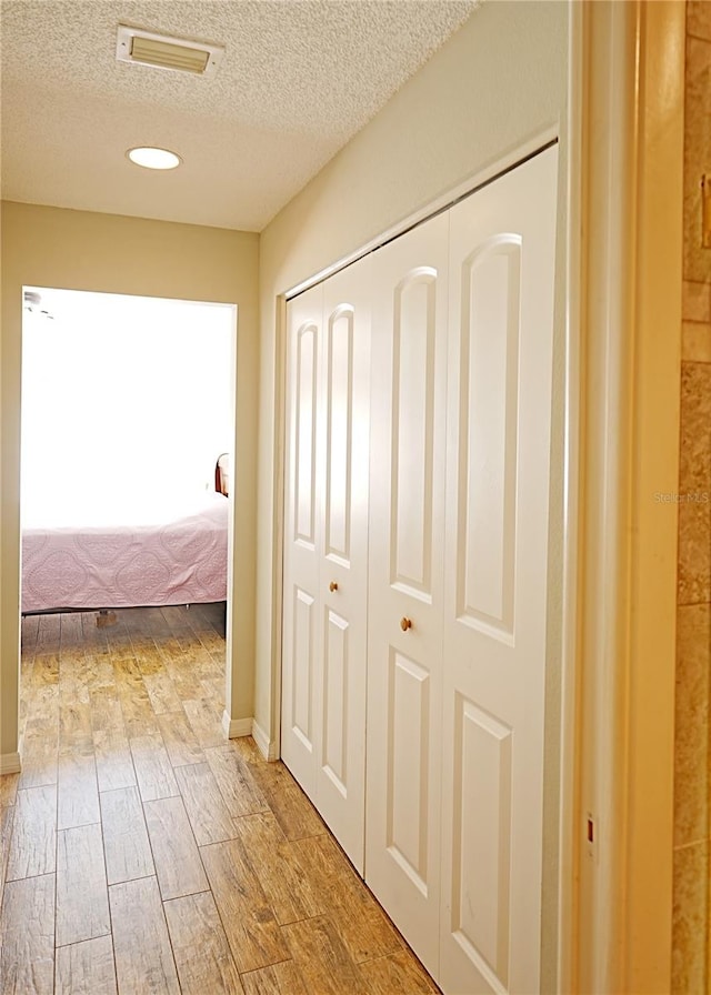 corridor featuring a textured ceiling and wood-type flooring