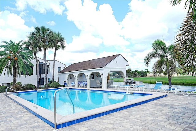 view of pool featuring a patio, an outdoor structure, and a water view