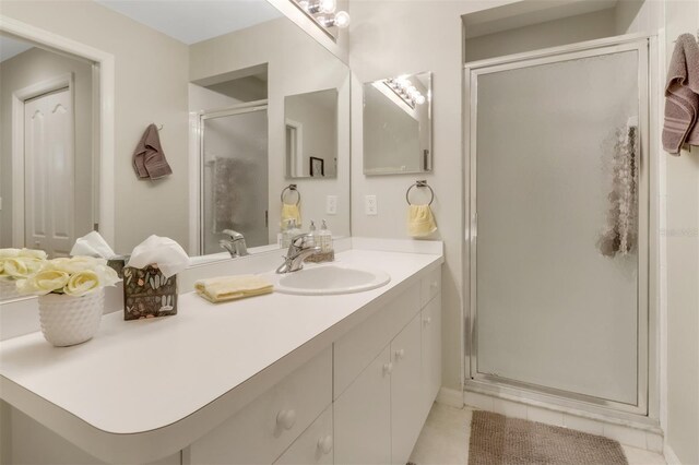 bathroom featuring tile patterned flooring, a shower with door, and vanity