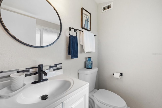 bathroom featuring decorative backsplash, vanity, and toilet