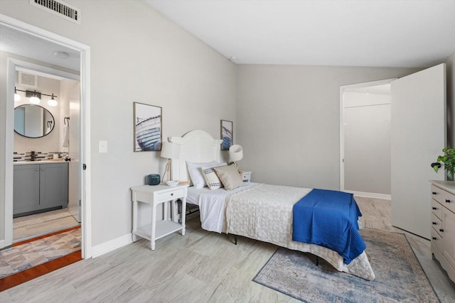 bedroom featuring ensuite bathroom, lofted ceiling, and light hardwood / wood-style floors