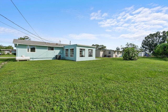 rear view of property with cooling unit and a yard