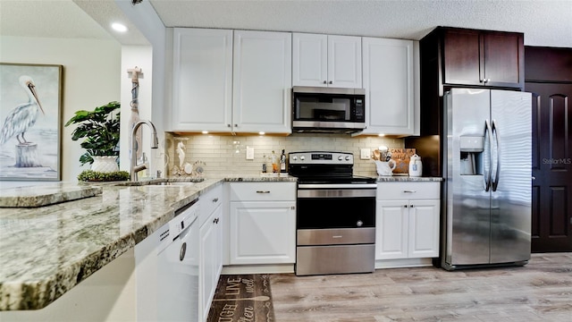 kitchen with sink, decorative backsplash, stainless steel appliances, and white cabinets