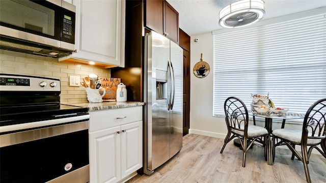 kitchen featuring appliances with stainless steel finishes, tasteful backsplash, a textured ceiling, white cabinets, and light hardwood / wood-style floors