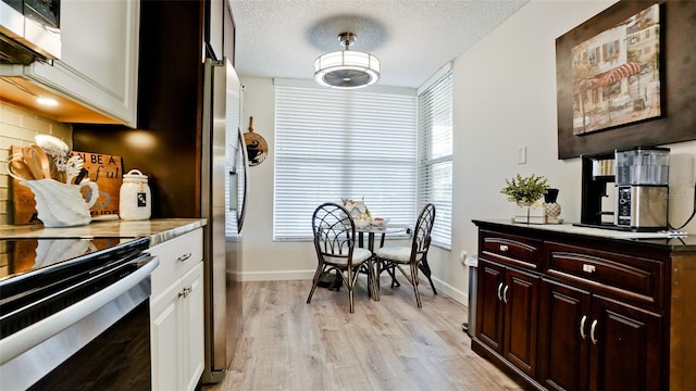 kitchen featuring stainless steel refrigerator with ice dispenser, light hardwood / wood-style flooring, electric range, a textured ceiling, and tasteful backsplash