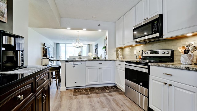 kitchen with white cabinets, light stone countertops, kitchen peninsula, and appliances with stainless steel finishes