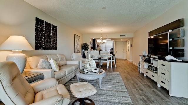 living room with a chandelier, hardwood / wood-style floors, and a textured ceiling