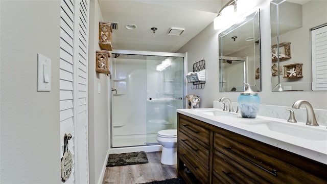 bathroom featuring a shower with door, vanity, wood-type flooring, and toilet