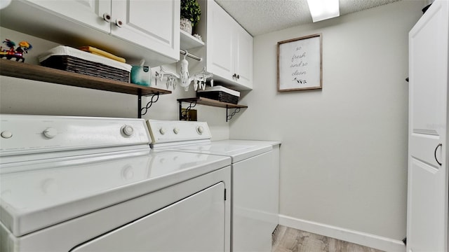 washroom with cabinets, a textured ceiling, light hardwood / wood-style floors, and washer and clothes dryer