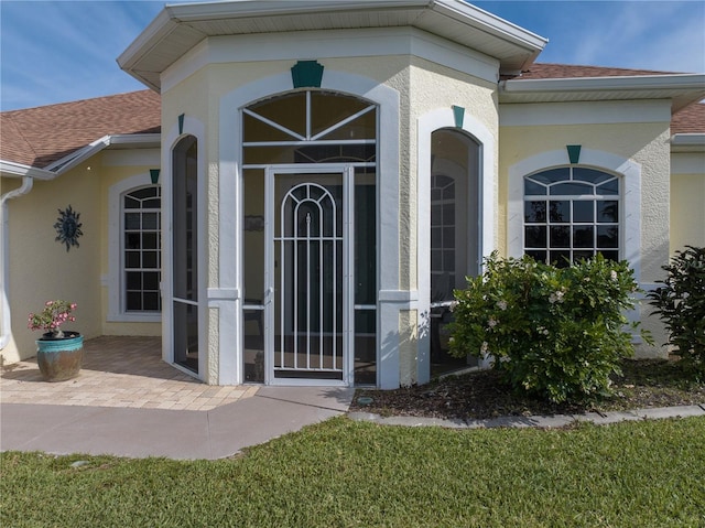 view of exterior entry featuring a lawn