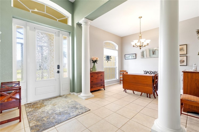 tiled foyer featuring an inviting chandelier, ornate columns, and a healthy amount of sunlight