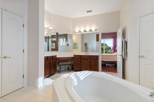 bathroom with tile patterned floors, tiled bath, and vanity