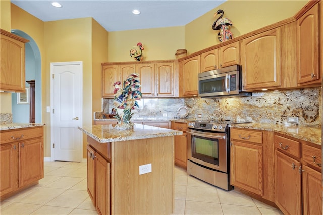 kitchen with stainless steel appliances, light stone counters, and a center island