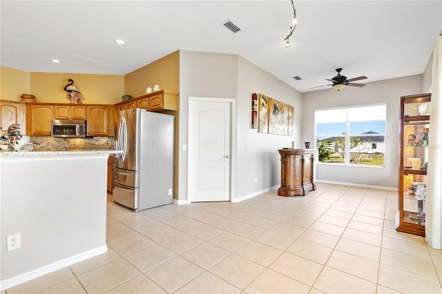 kitchen featuring light stone counters, ceiling fan, light tile patterned floors, tasteful backsplash, and stainless steel appliances