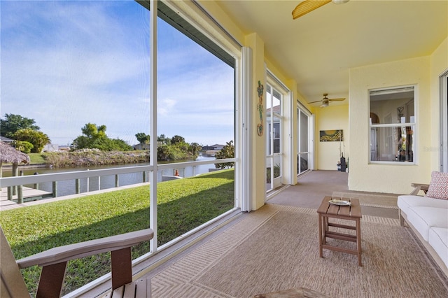 sunroom / solarium with ceiling fan and a water view