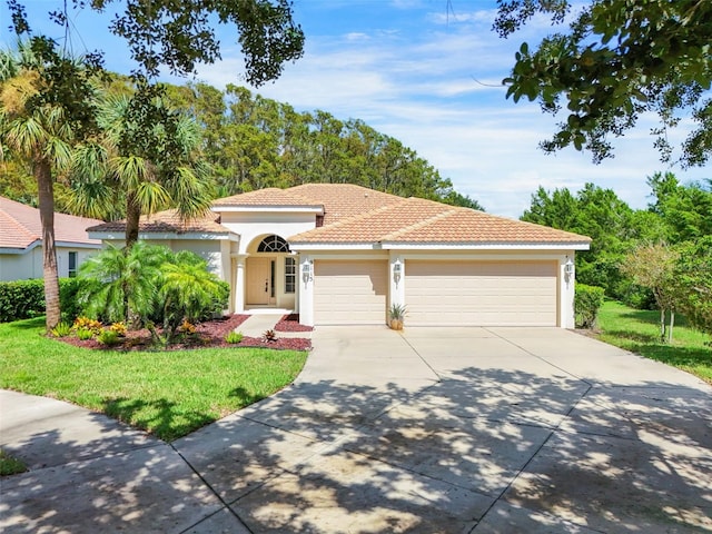 mediterranean / spanish-style home with a garage and a front lawn