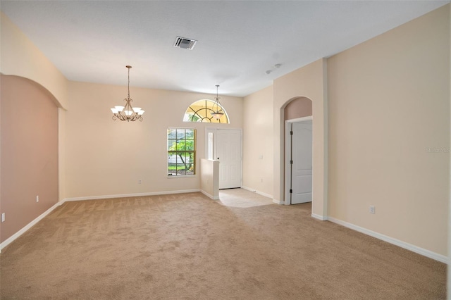 empty room with a chandelier and light colored carpet