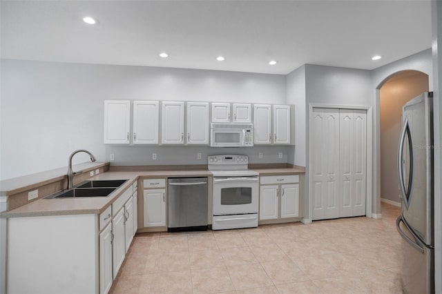 kitchen featuring light tile patterned flooring, white cabinets, appliances with stainless steel finishes, and sink