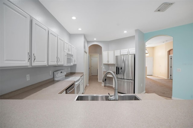 kitchen featuring light colored carpet, sink, stainless steel appliances, and white cabinets