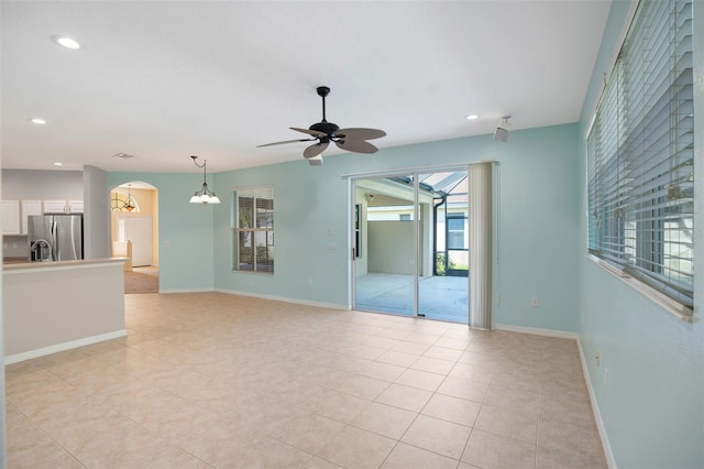 tiled spare room with ceiling fan with notable chandelier