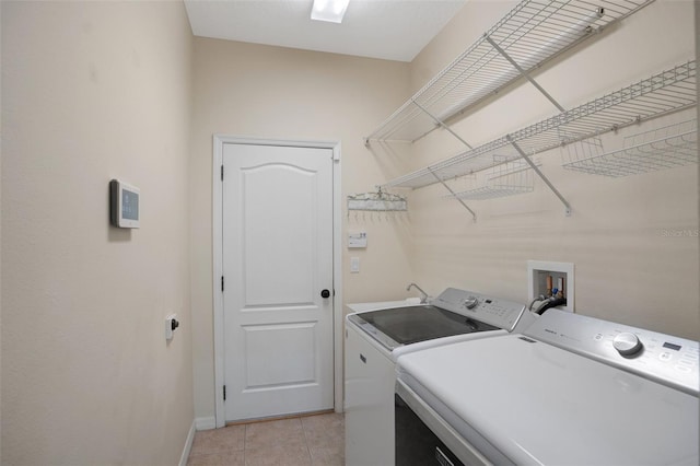 clothes washing area featuring washing machine and dryer, sink, and light tile patterned floors