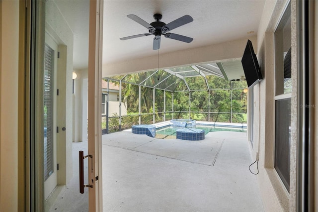 view of patio / terrace featuring glass enclosure, a swimming pool with hot tub, and ceiling fan