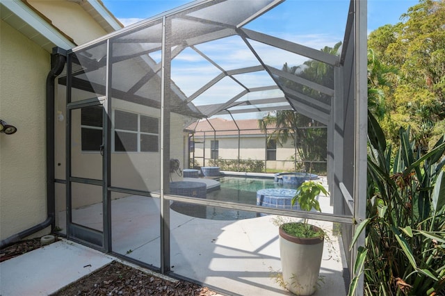 view of pool with glass enclosure, an in ground hot tub, and a patio area