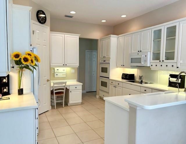 kitchen featuring white appliances, white cabinetry, light tile patterned floors, and kitchen peninsula