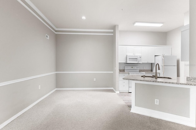 kitchen featuring white cabinetry, white appliances, light stone countertops, sink, and light carpet