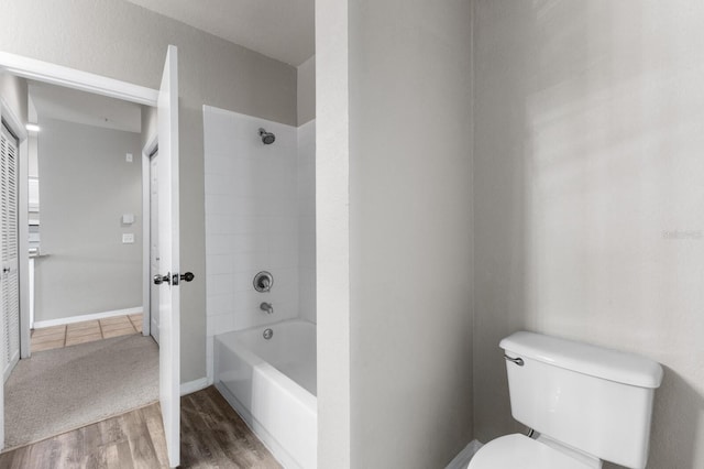 bathroom with tiled shower / bath, hardwood / wood-style floors, and toilet