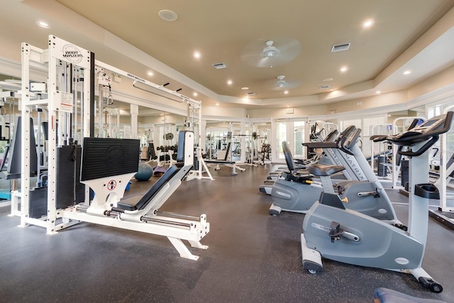 exercise room with ceiling fan and a raised ceiling