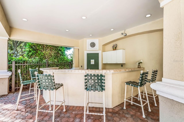 kitchen featuring white cabinets, tile countertops, a kitchen bar, and kitchen peninsula