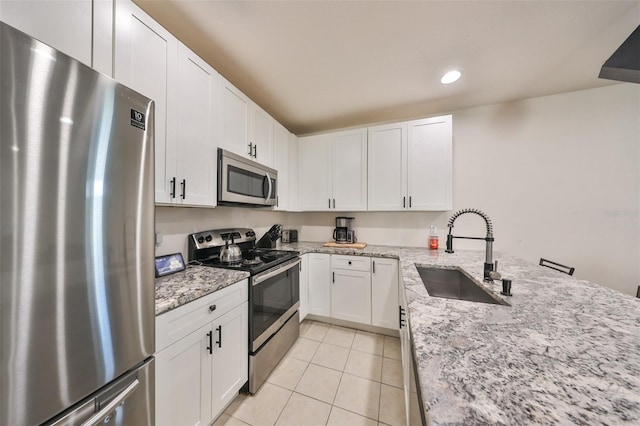 kitchen with light stone counters, white cabinets, stainless steel appliances, and sink