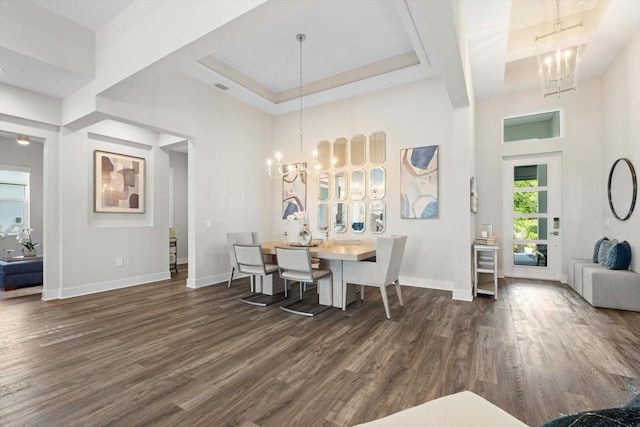 dining room with a raised ceiling, dark hardwood / wood-style flooring, and a chandelier