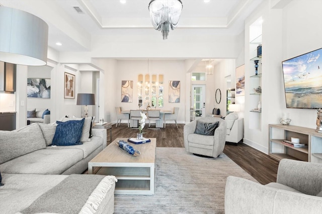 living room with hardwood / wood-style flooring, a raised ceiling, and a chandelier