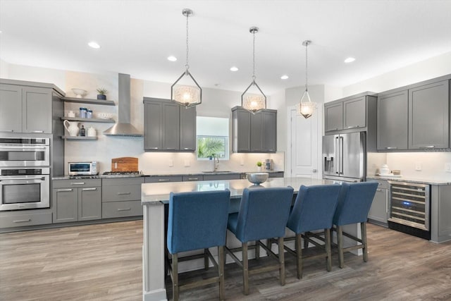 kitchen featuring gray cabinetry, sink, wall chimney exhaust hood, beverage cooler, and appliances with stainless steel finishes