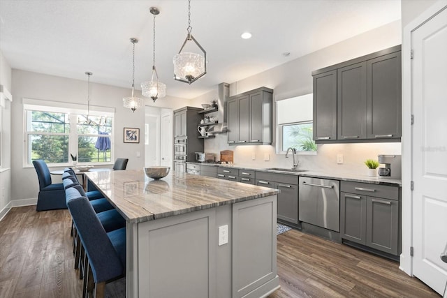 kitchen featuring sink, stainless steel appliances, decorative light fixtures, gray cabinets, and a kitchen island