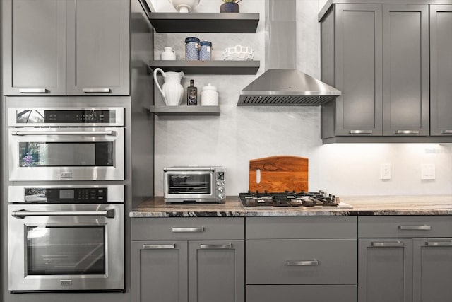 kitchen with gray cabinets, wall chimney exhaust hood, and appliances with stainless steel finishes