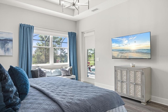 bedroom featuring multiple windows, hardwood / wood-style floors, and an inviting chandelier